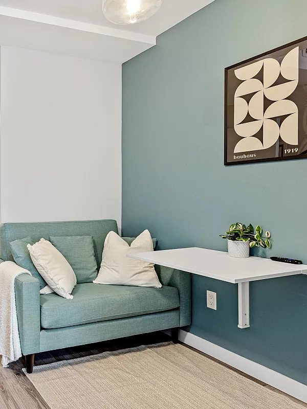 Cozy apartment showcasing a modern open-concept layout with a vibrant teal accent wall, stylish seating area, and elegant granite countertop kitchen.
