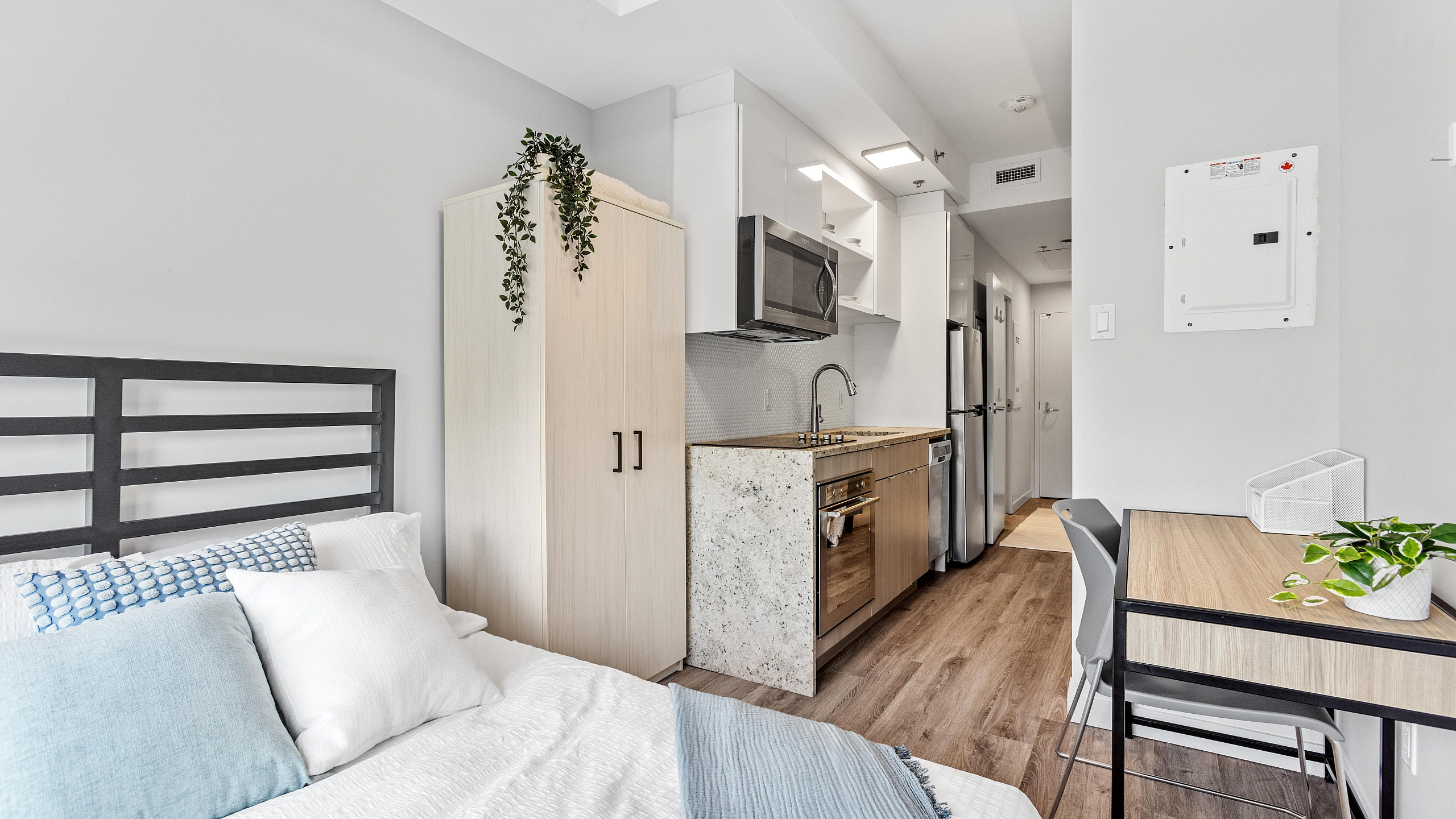 Modern studio apartment with sleek kitchen, cozy bed, and a stylish workspace. Ideal for city living.