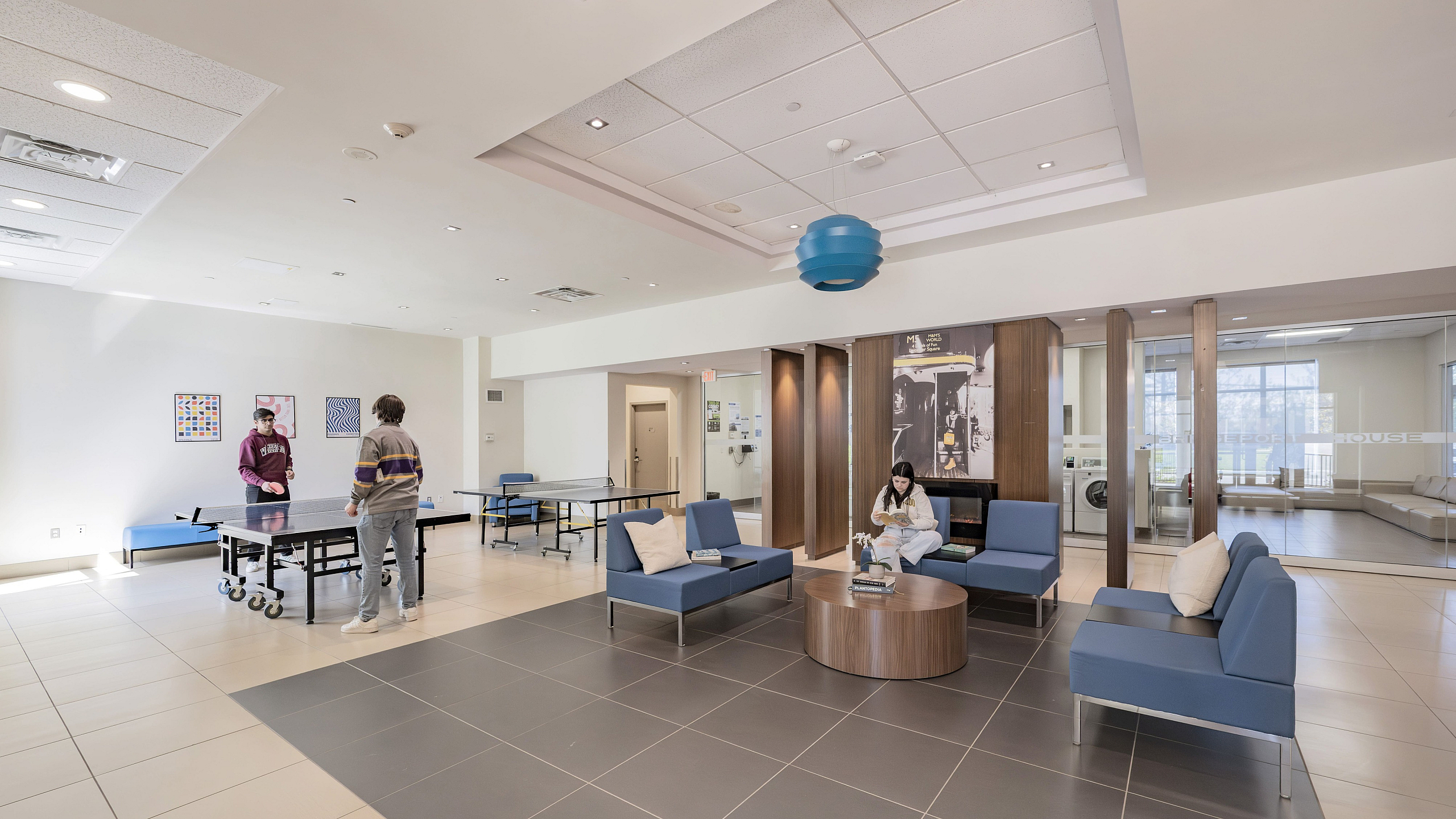 Bright and spacious recreation room featuring modern seating, a ping pong table, and stylish d&eacute;cor.