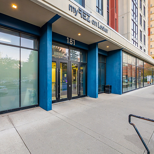Modern apartment entrance with striking blue facade and large windows, offering a welcoming atmosphere in an urban setting.