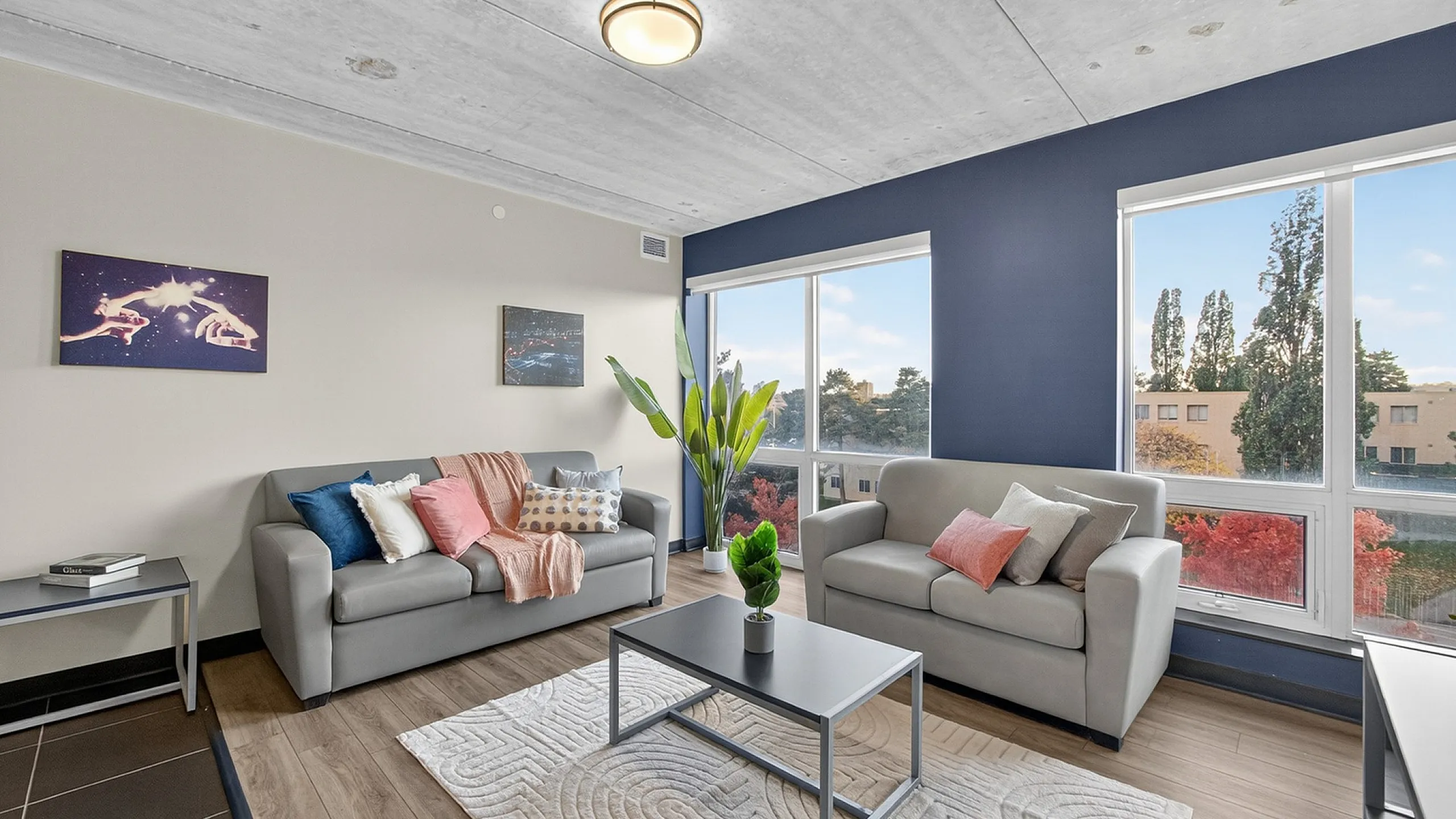 Bright and modern living room with stylish gray sofas, vibrant decor, and large windows offering a stunning view.