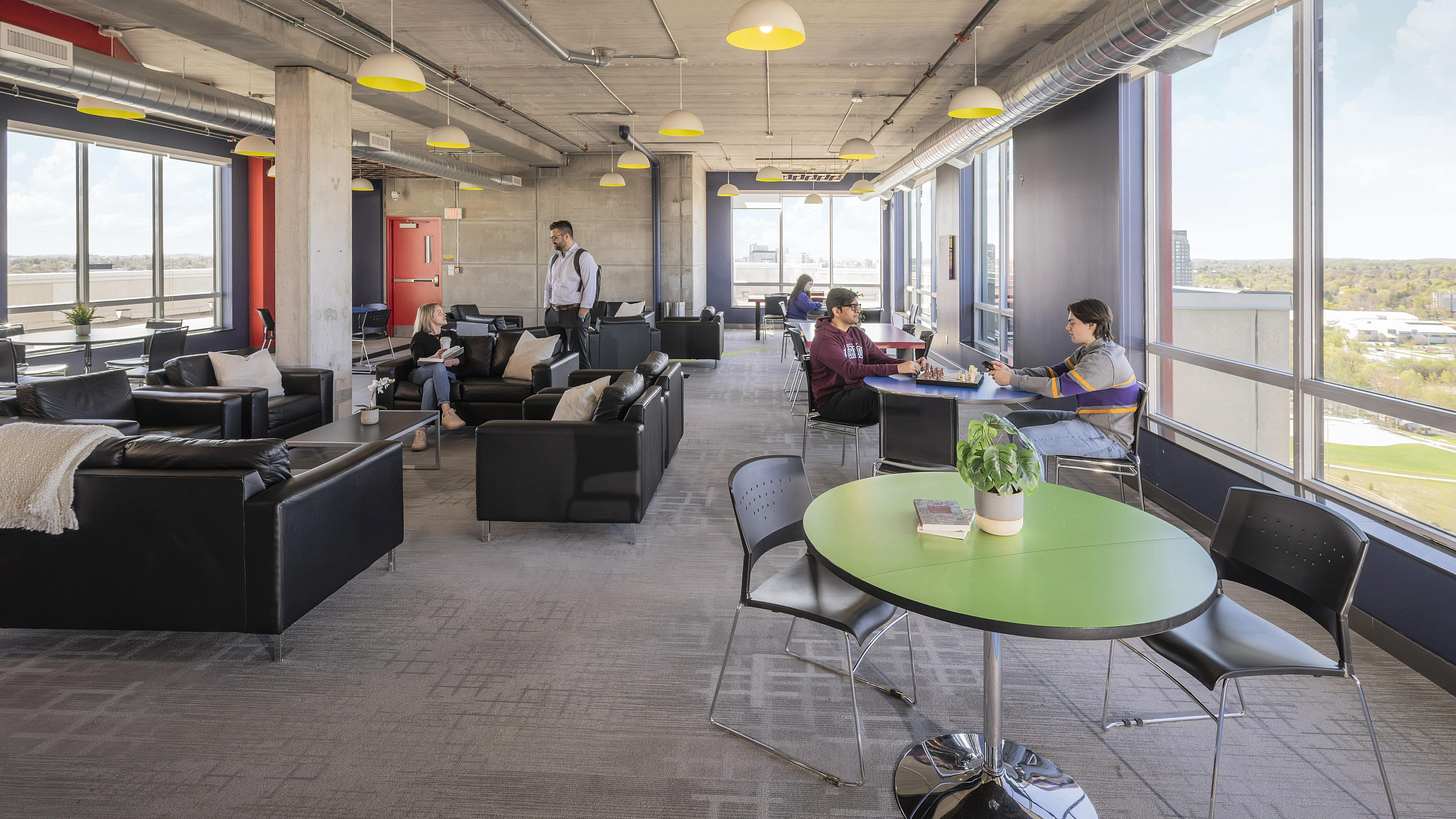 Modern open-layout lounge with plush seating, vibrant lighting, and expansive windows offering stunning city views.