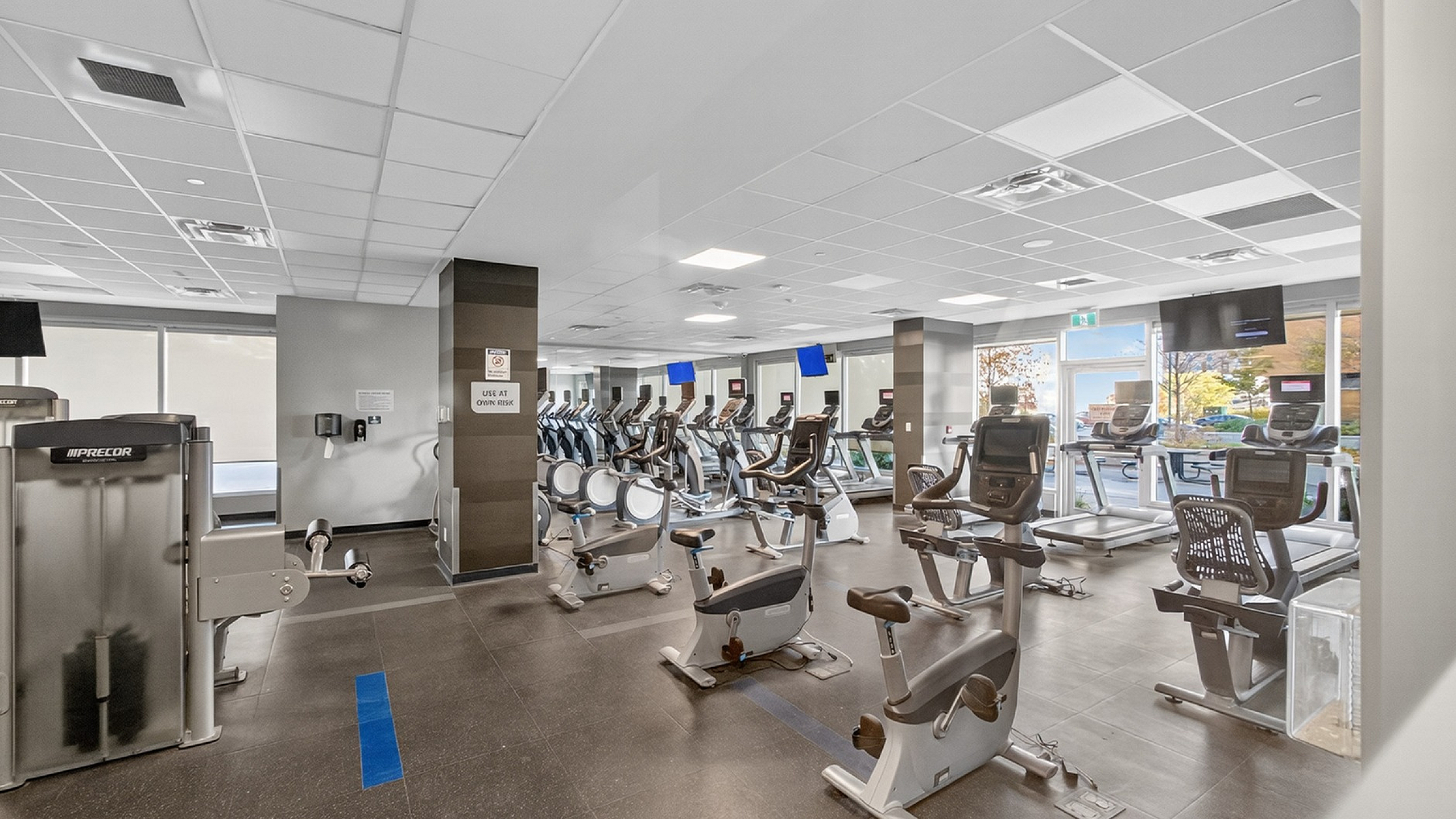 Modern fitness center with state-of-the-art exercise equipment, including treadmills and stationary bikes, flooded with natural light.