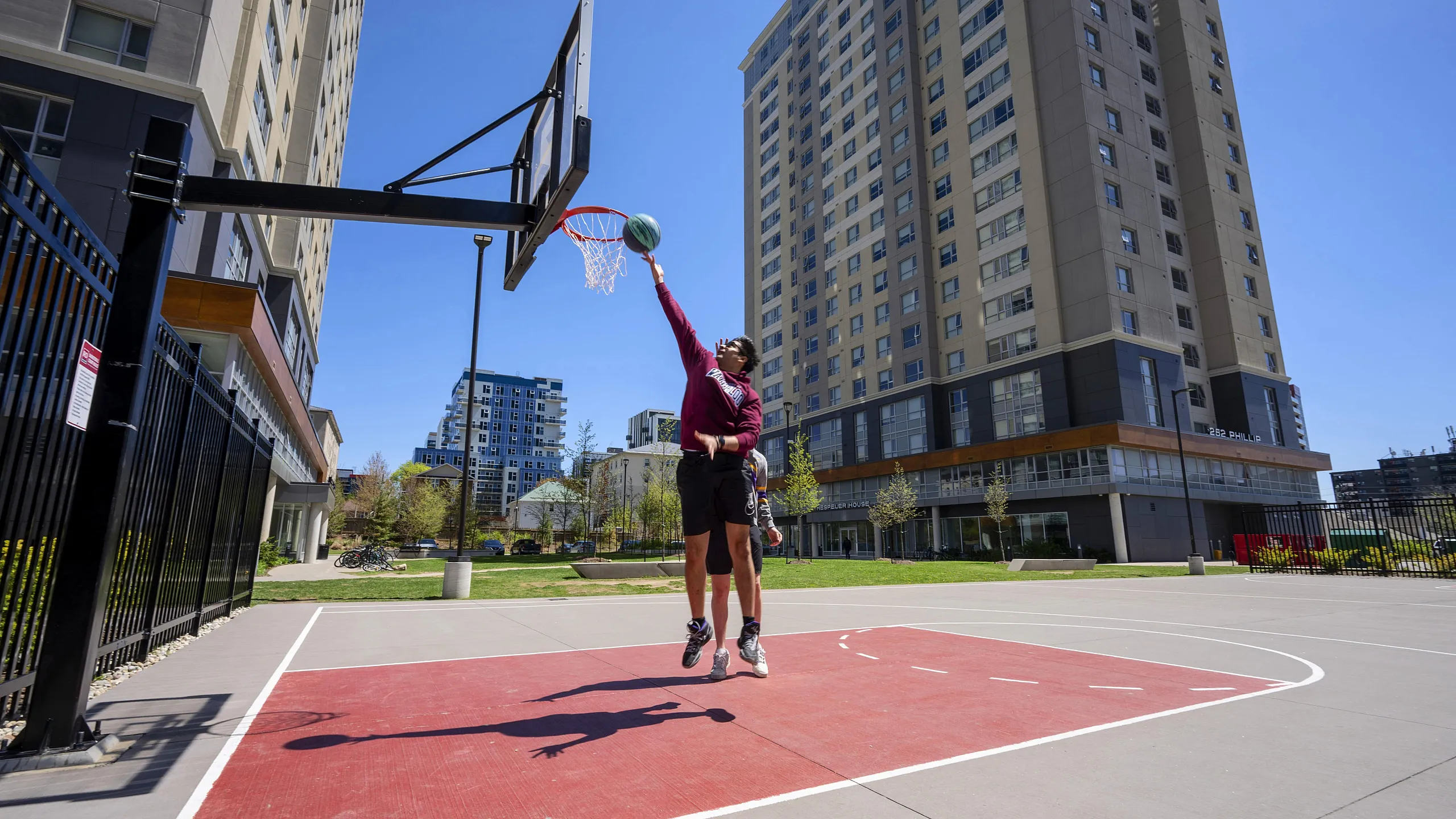 Modern apartment complex with a vibrant outdoor basketball court, perfect for active lifestyles in a lively urban setting.
