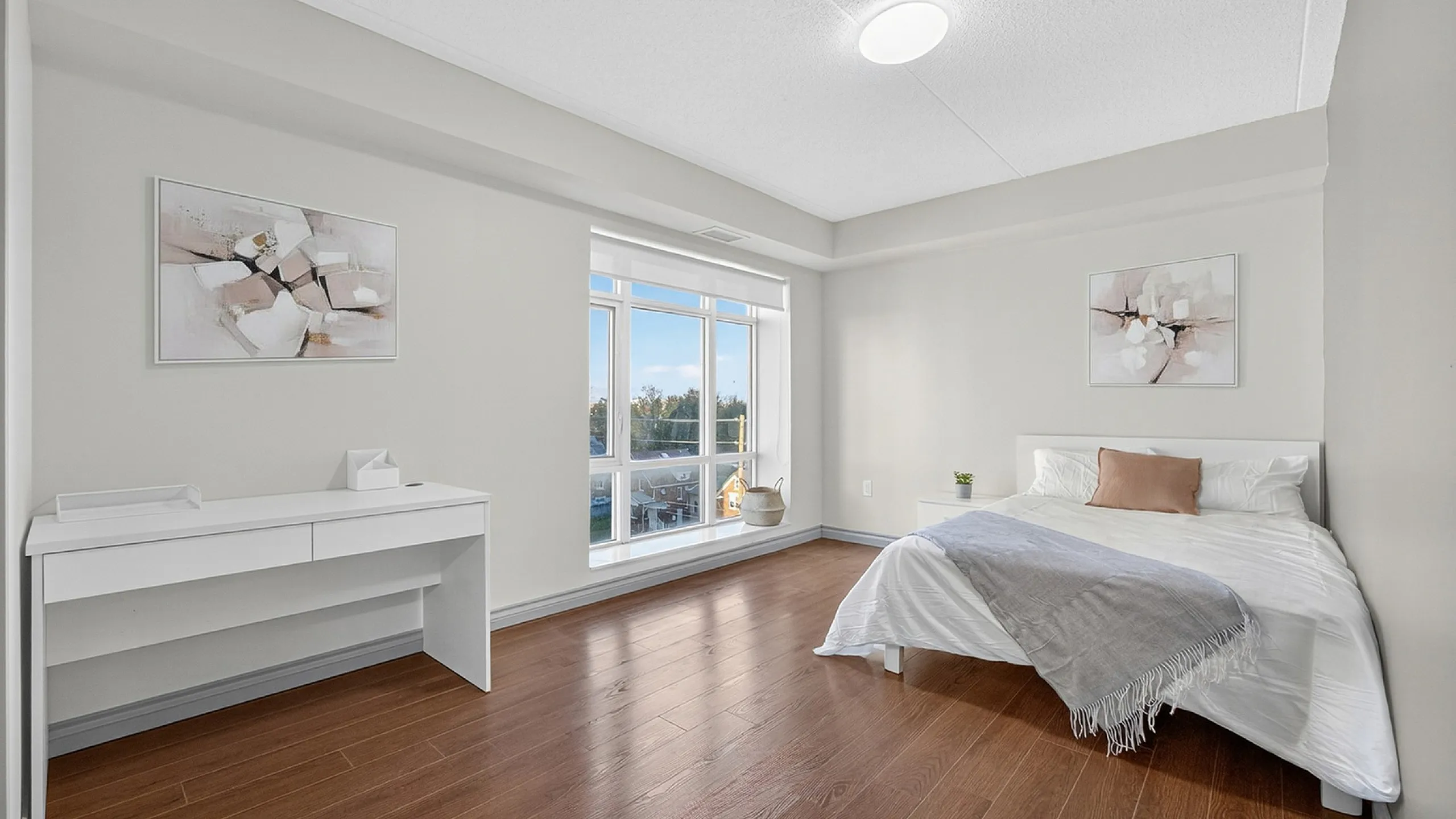 Bright, airy bedroom featuring modern decor, a sleek desk, and large windows with picturesque views.