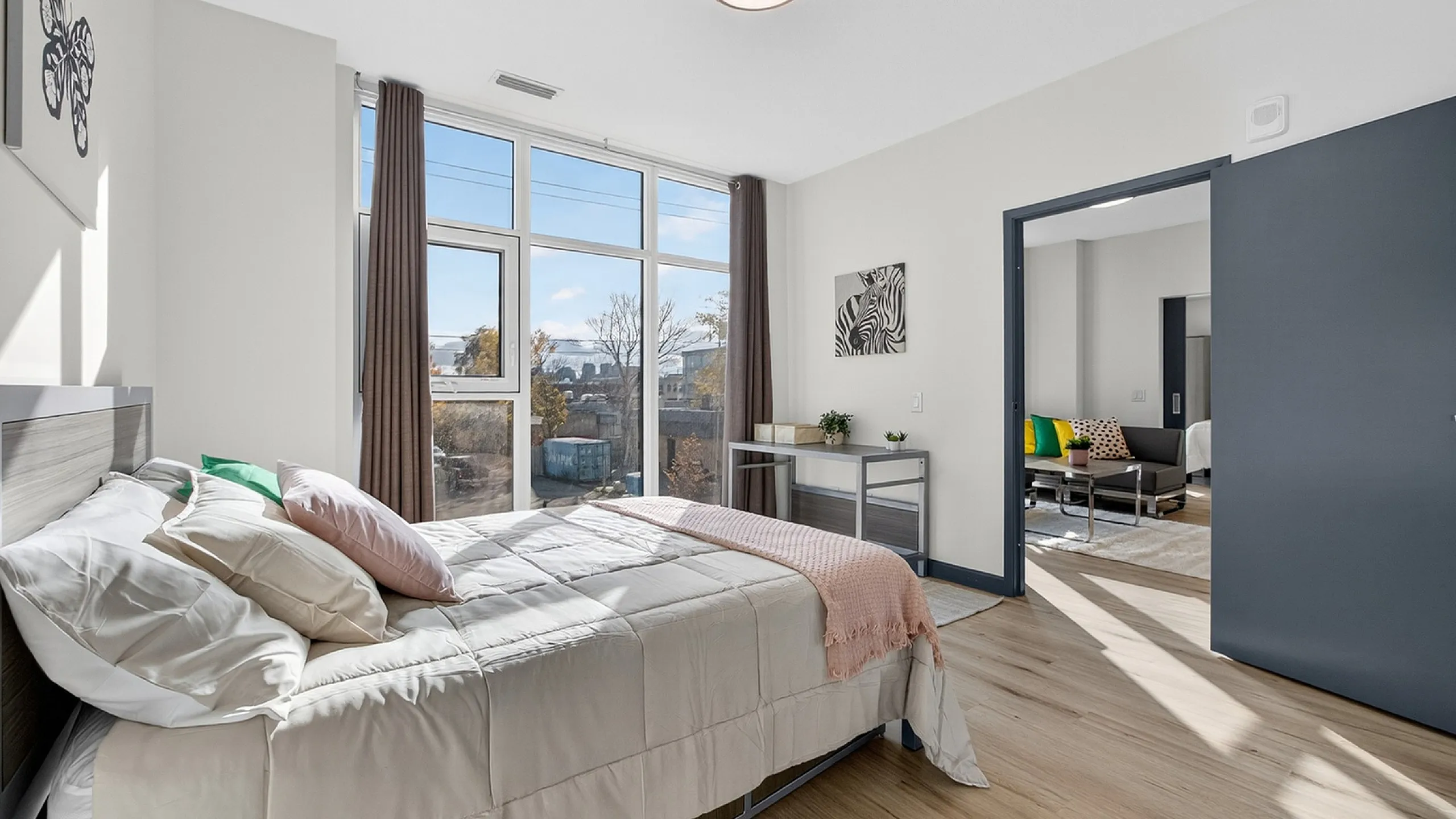 Bright and modern bedroom with large windows and cozy decor, offering a glimpse into a stylish living area.