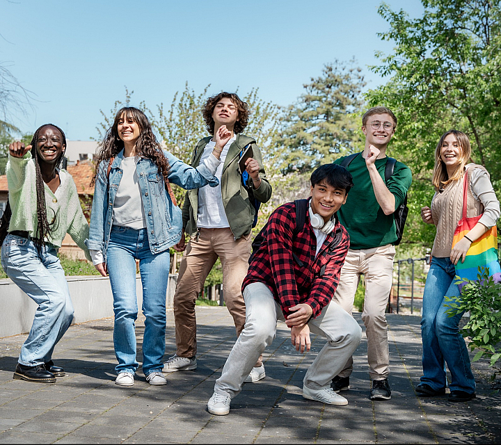 Group of happy young adults enjoying a sunny day outdoors, surrounded by lush greenery and a clear blue sky.