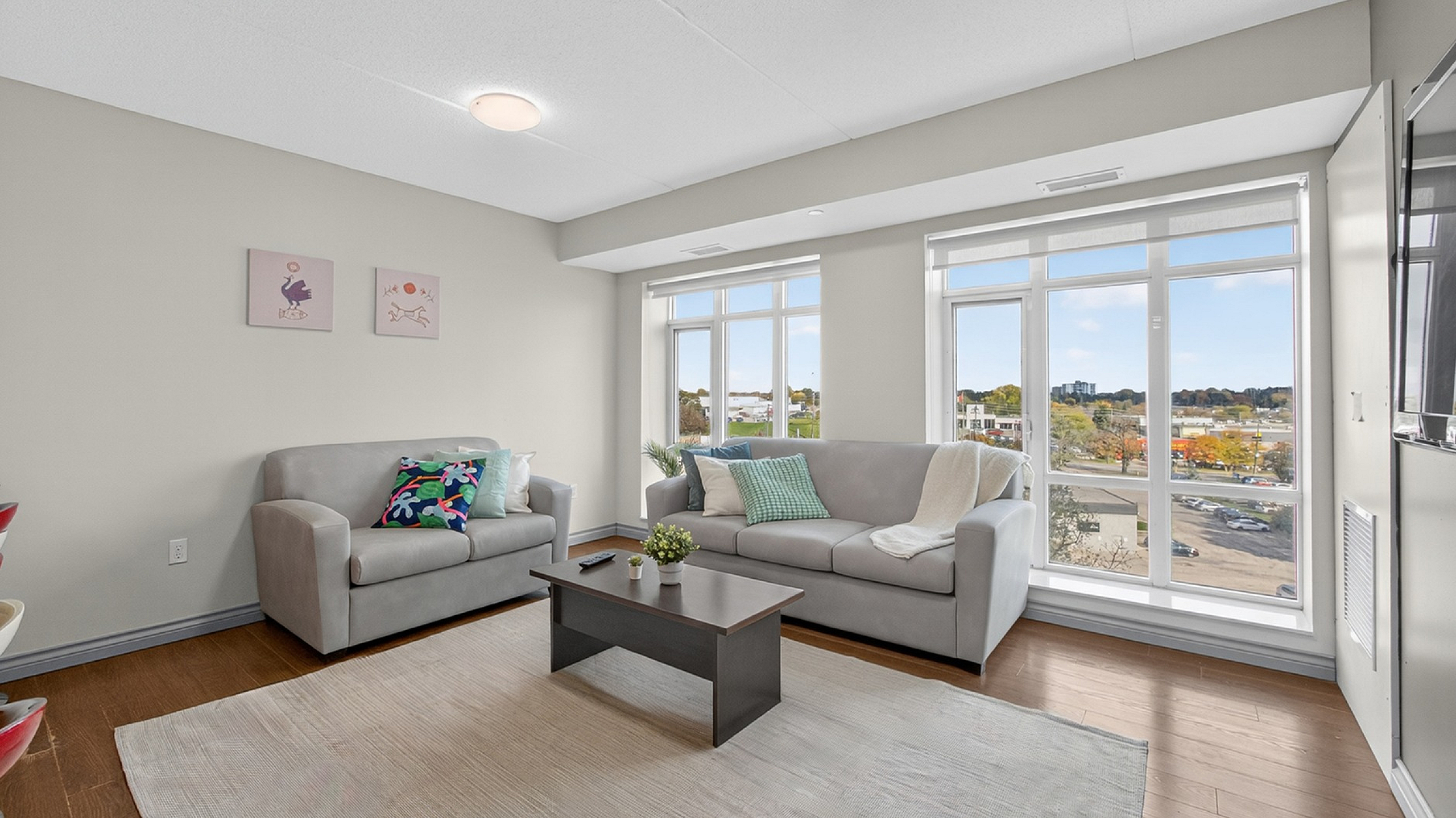 Bright and inviting living room with large windows, cozy gray sofas, and elegant decor offering a relaxing atmosphere and scenic views.