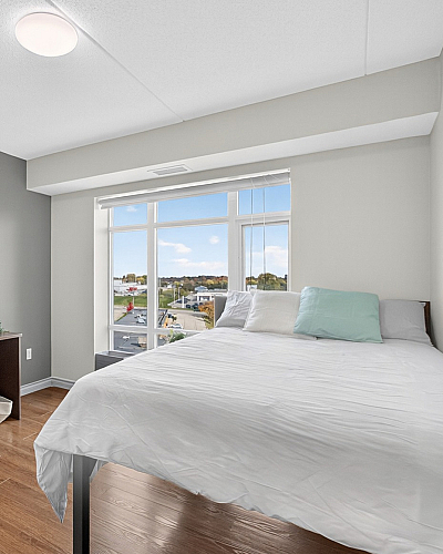 Bright bedroom with large window view, featuring elegant hardwood floors and a stylish desk.