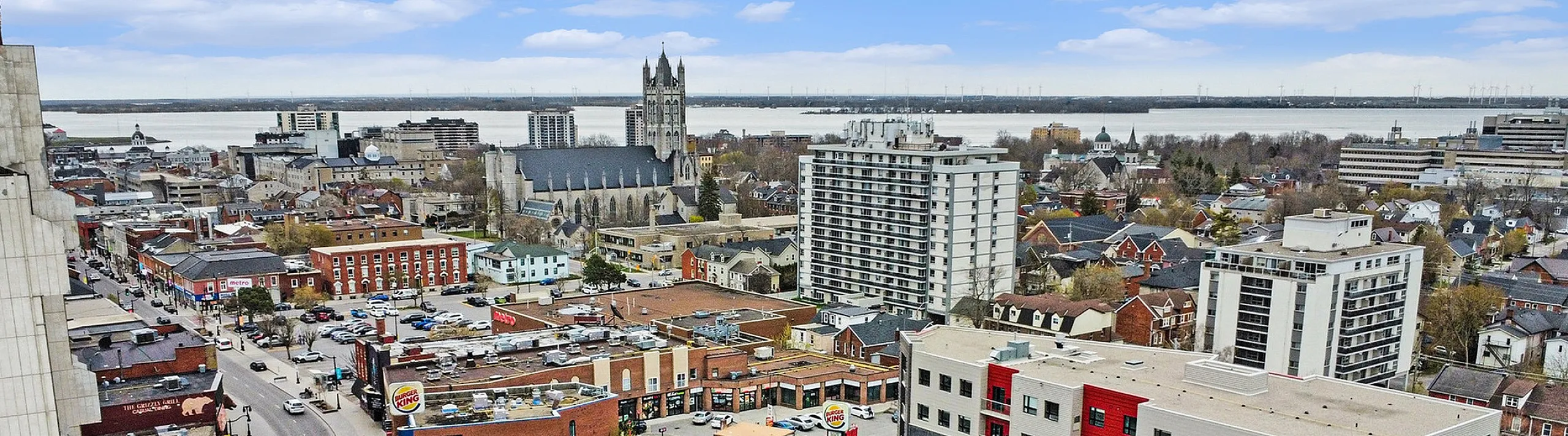 Vibrant cityscape featuring modern apartments and bustling streets with a scenic riverside backdrop.