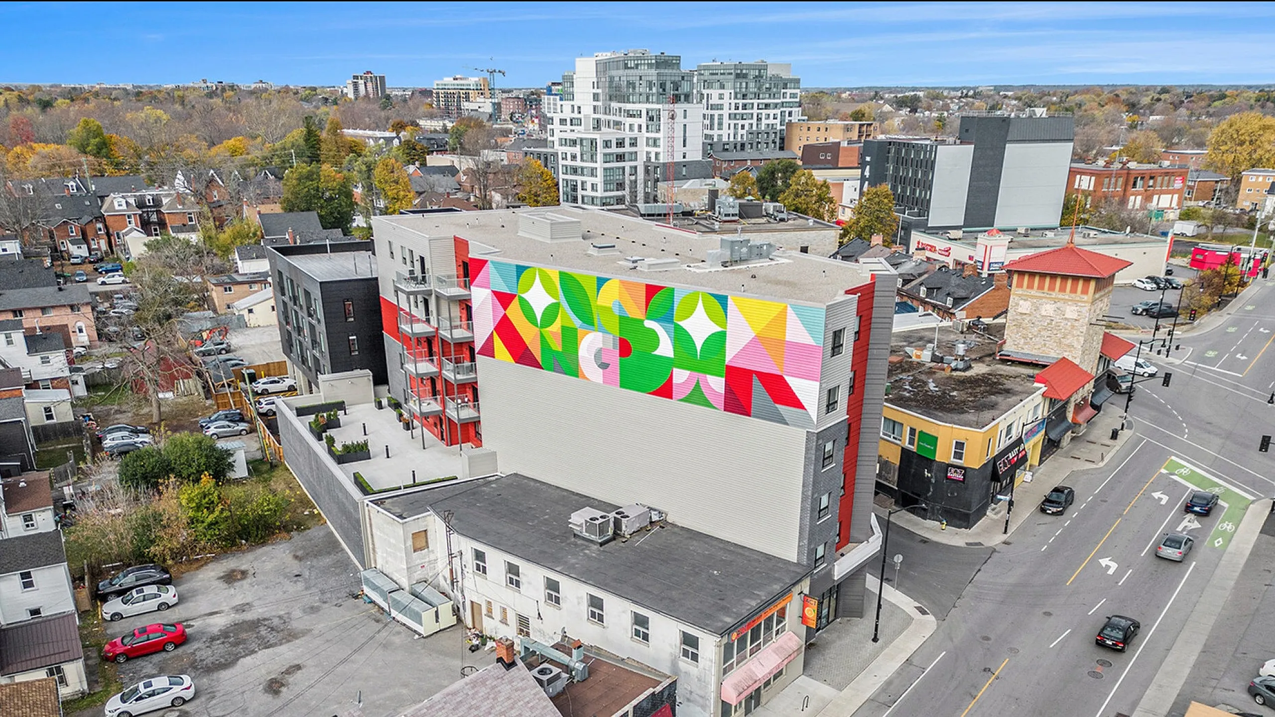 Vibrant urban living with a colorful mural on a modern apartment building, surrounded by a bustling neighborhood and city streets.