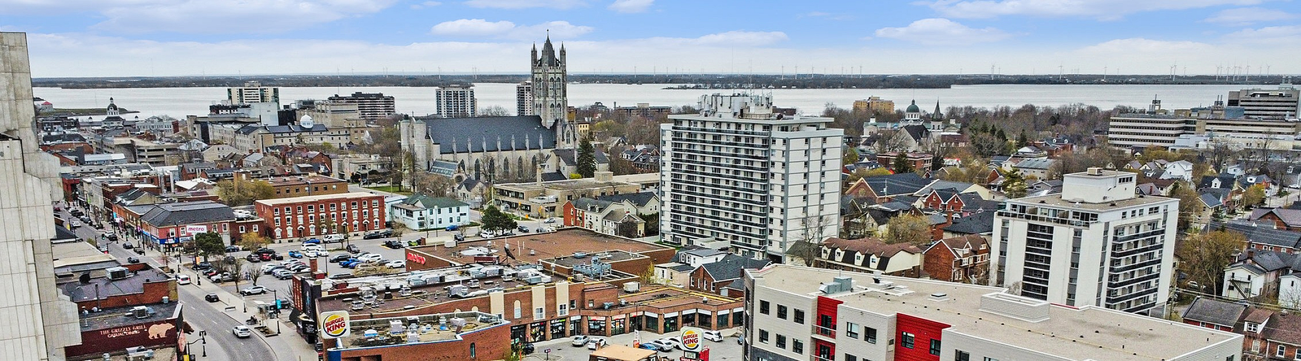 Vibrant cityscape view showcasing dynamic urban architecture, lively street with popular stores, and picturesque riverside in the distance.