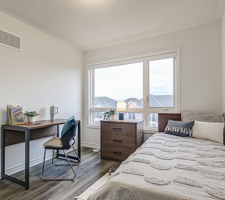 Bright and cozy bedroom with a modern desk, large window, and comfortable single bed, perfect for a serene living space.