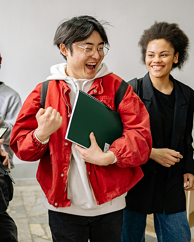 Group of diverse, joyful students socializing on stairs in a bright, modern building.