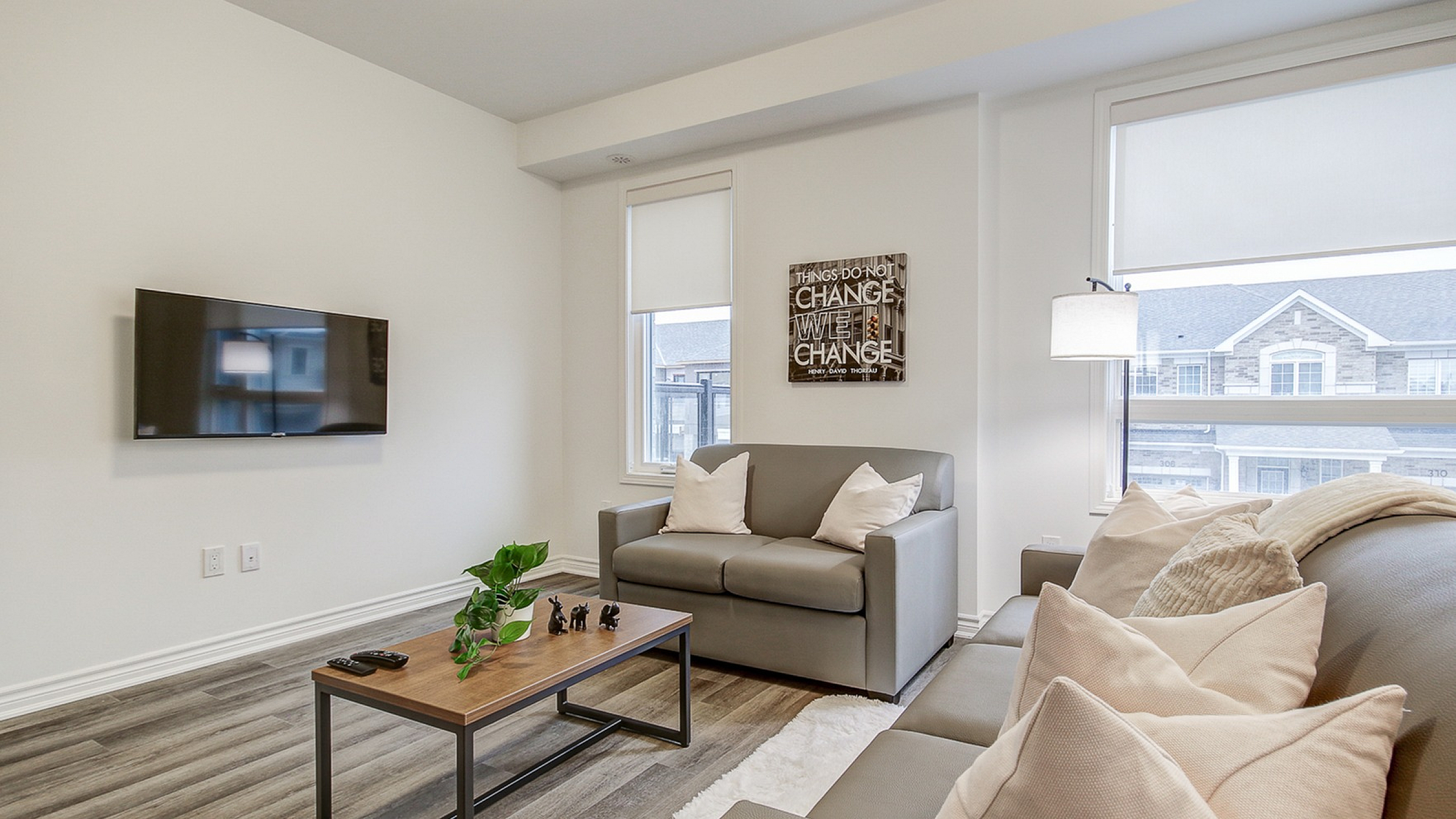 Chic and cozy living room featuring sleek sofas, modern decor, and abundant natural light from large windows overlooking charming architecture.