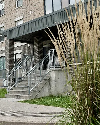 Charming apartment building with stylish brick facade, surrounded by lush greenery and inviting walkway.
