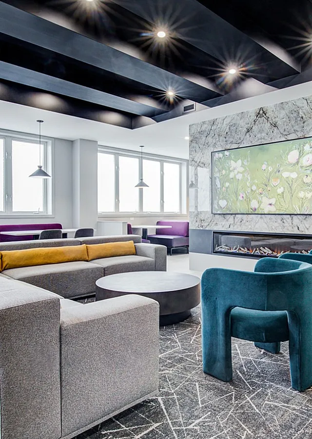 Contemporary lobby lounge with stylish seating, modern lighting, and a stunning stone accent wall featuring vibrant artwork.
