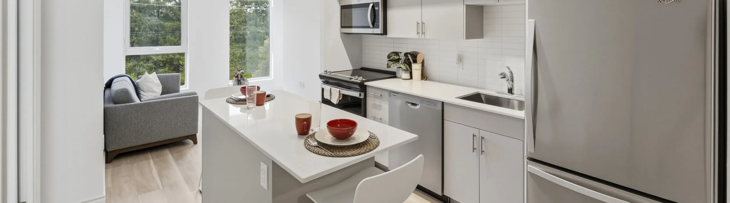 Bright, modern kitchen with sleek appliances and a cozy breakfast bar, adjoining a stylish living space with natural light.