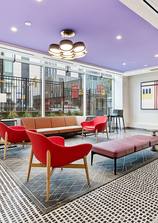 Chic modern lounge with vibrant red seating, artistic decor, and expansive windows for ample natural light.