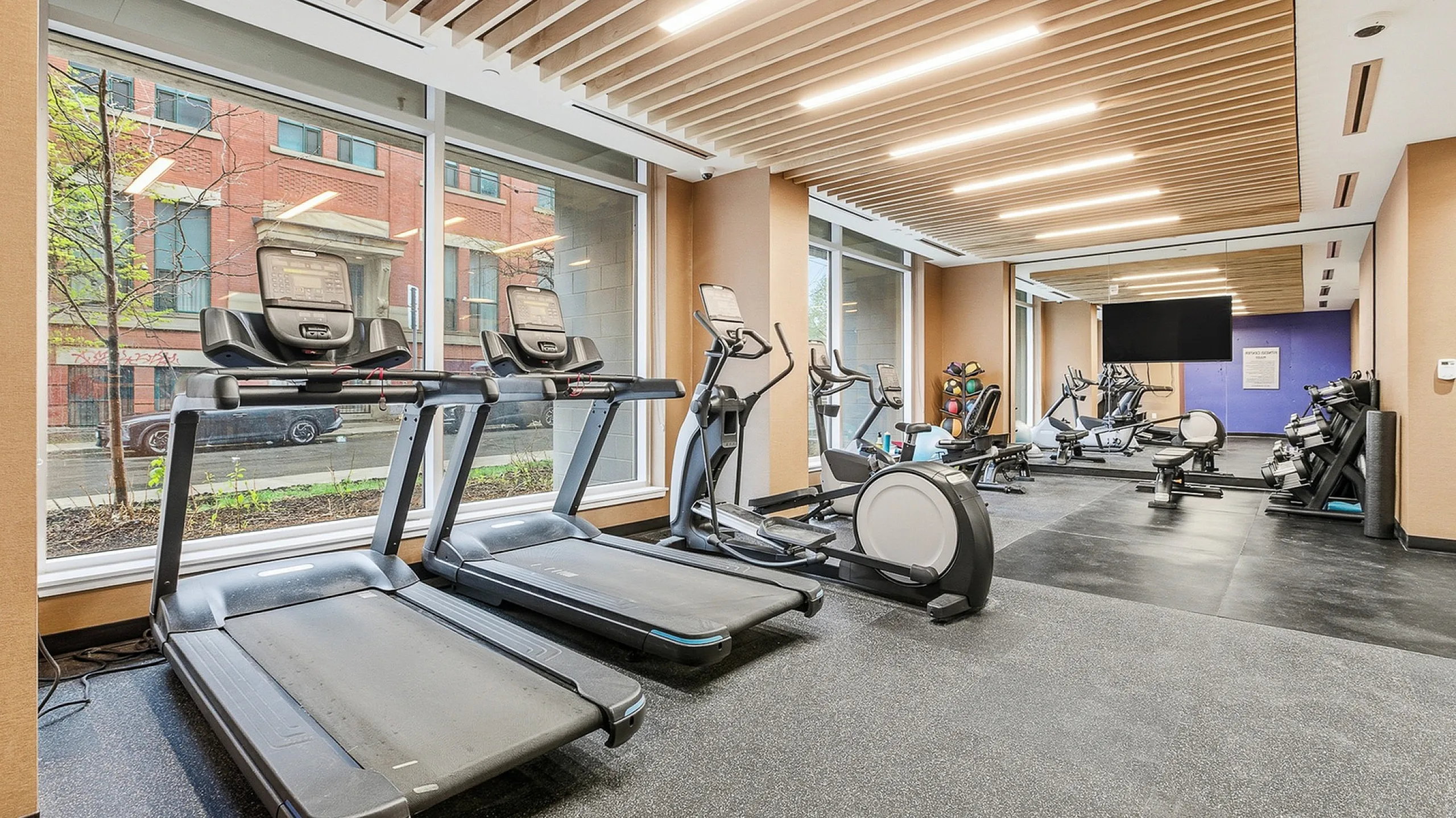 Modern fitness center with state-of-the-art exercise equipment, floor-to-ceiling windows, and bright, inviting atmosphere.