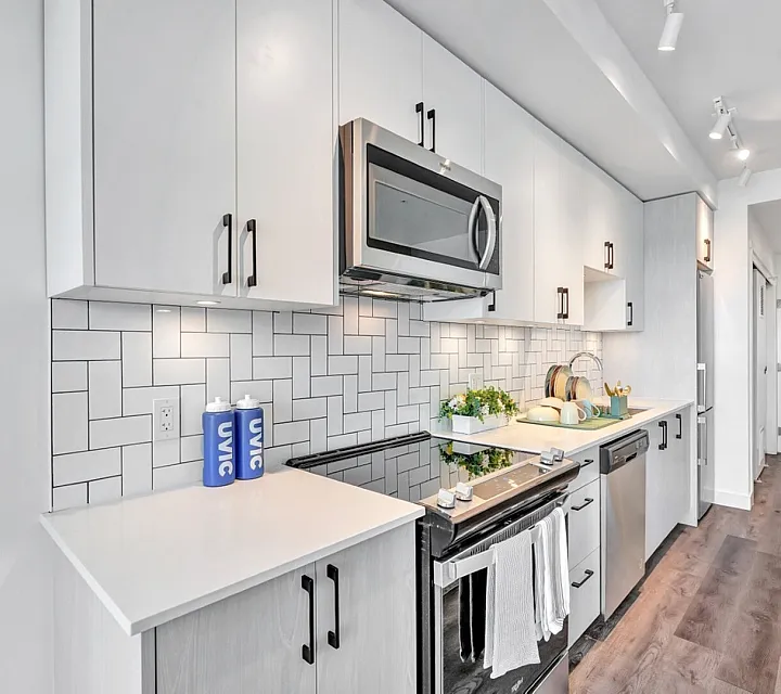 Modern kitchen with sleek white cabinetry, stainless steel appliances, and stylish tile backsplash, offering an elegant cooking space.