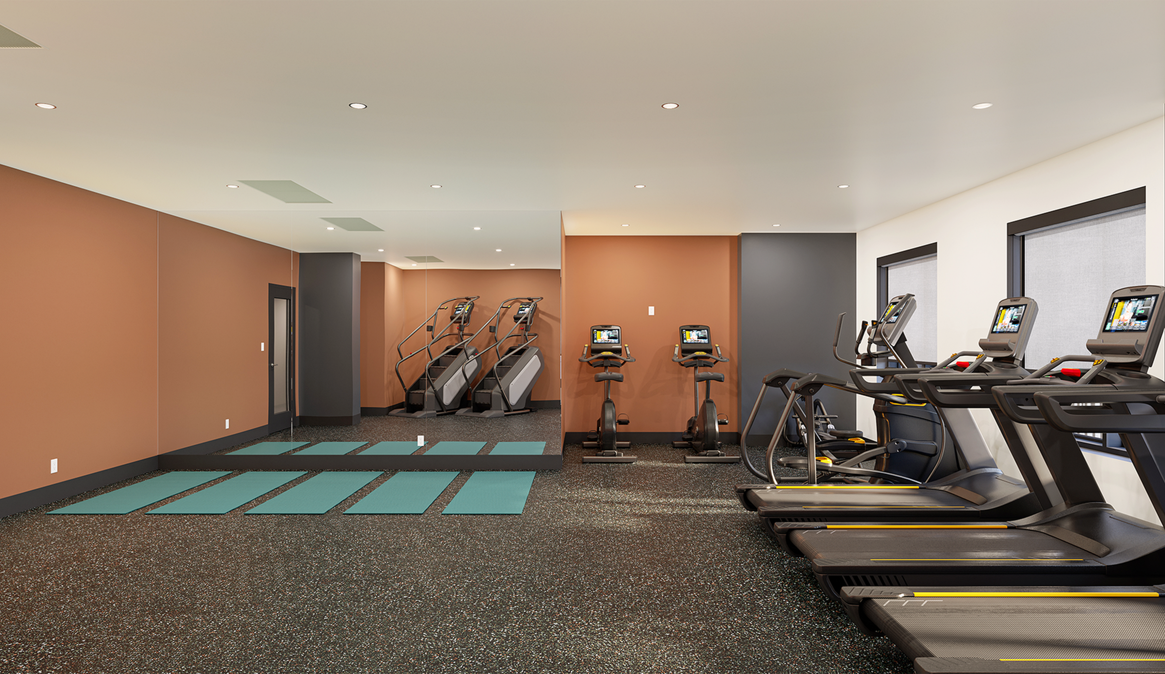 Modern fitness center featuring state-of-the-art treadmills, exercise bikes, and a serene yoga area with mats.