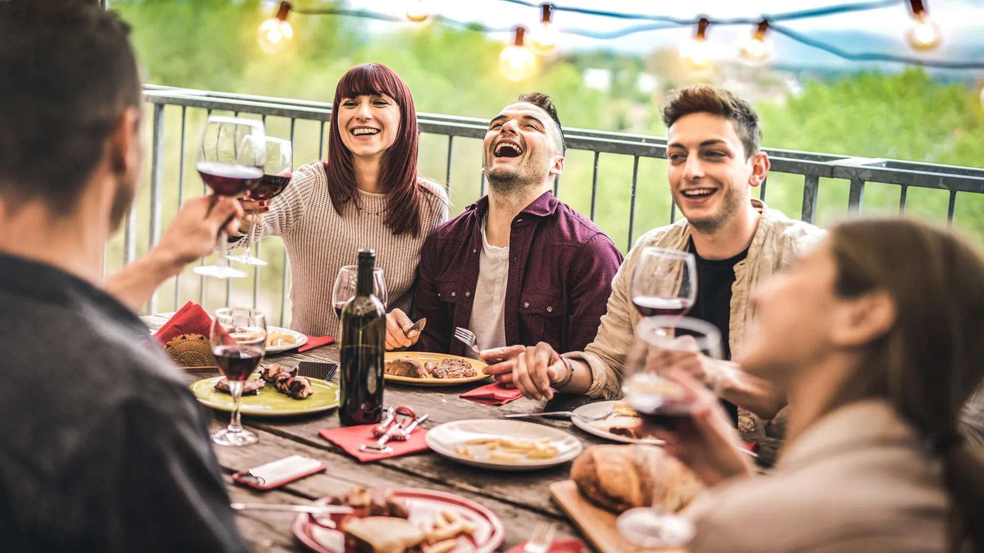 Friends sitting around a table laughing and sharing a meal in a walkable Salt Lake City neighborhood