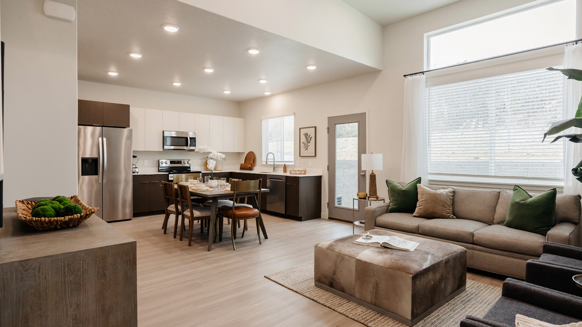 Open-concept Timberline living room and kitchen with wood-style floors, quartz countertops, and stainless steel appliances.