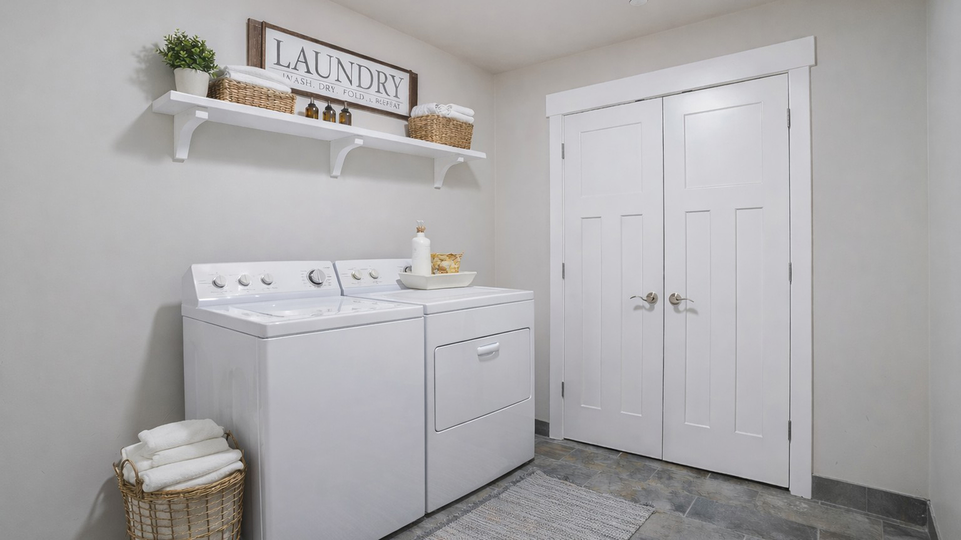 In-unit laundry room at Junction View Apartments featuring full-size washer and dryer with shelving and storage space.