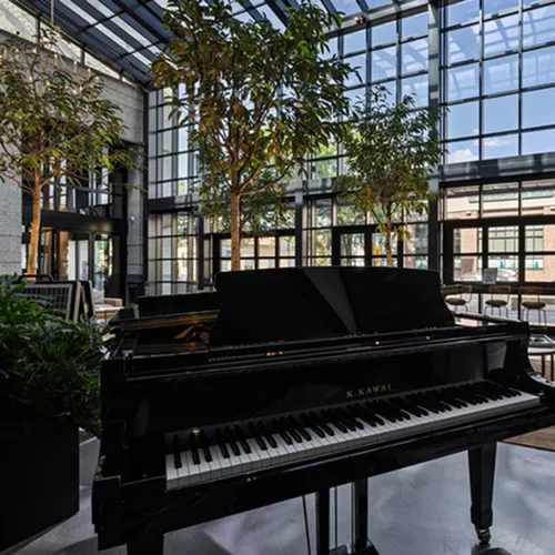 Grand piano inside Sugar Alley's glass atrium with natural light and modern luxury design