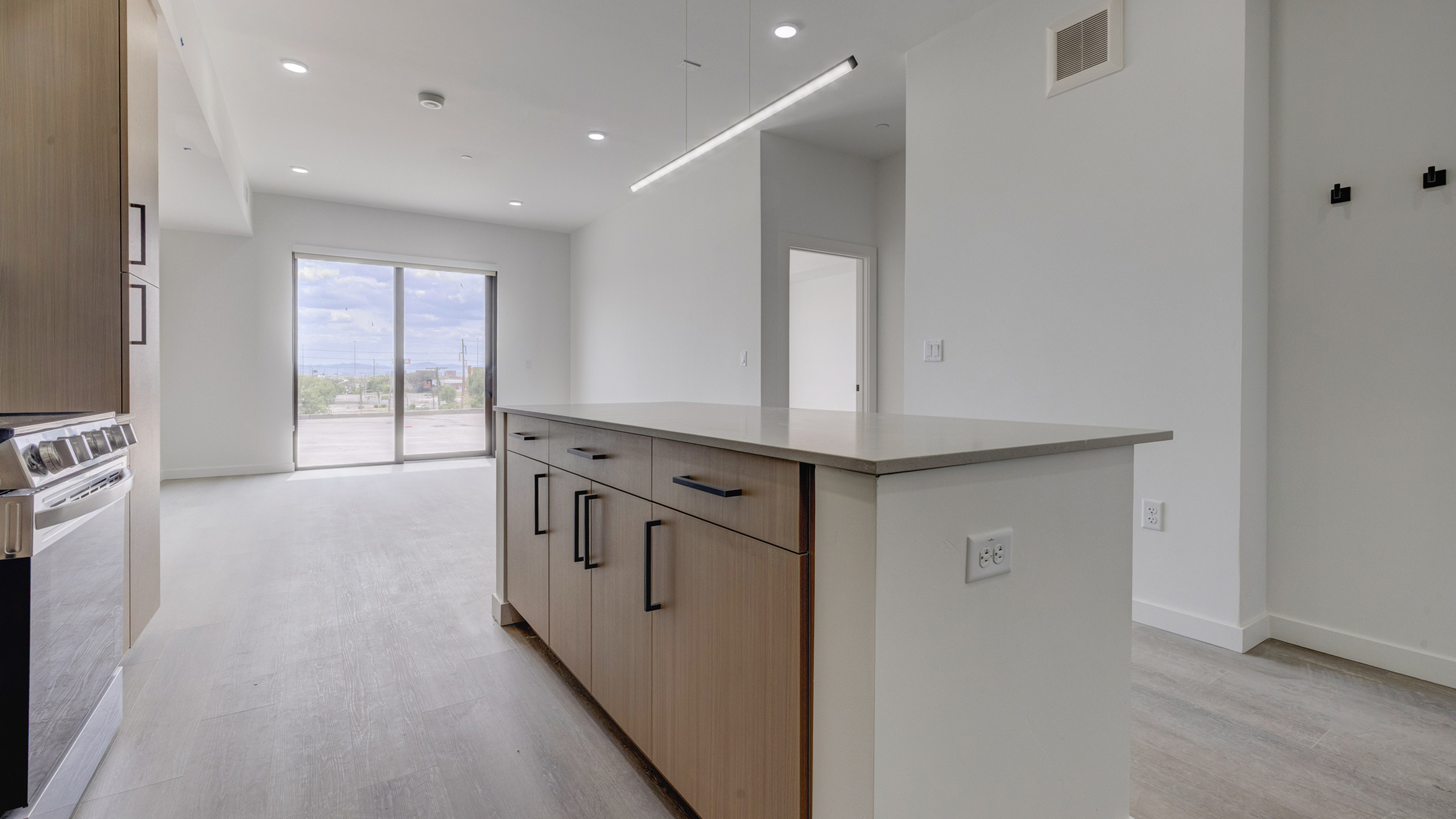 Open-concept apartment featuring a spacious kitchen island, quartz countertops, and modern living area at Bissinger & Co. in Salt Lake City.