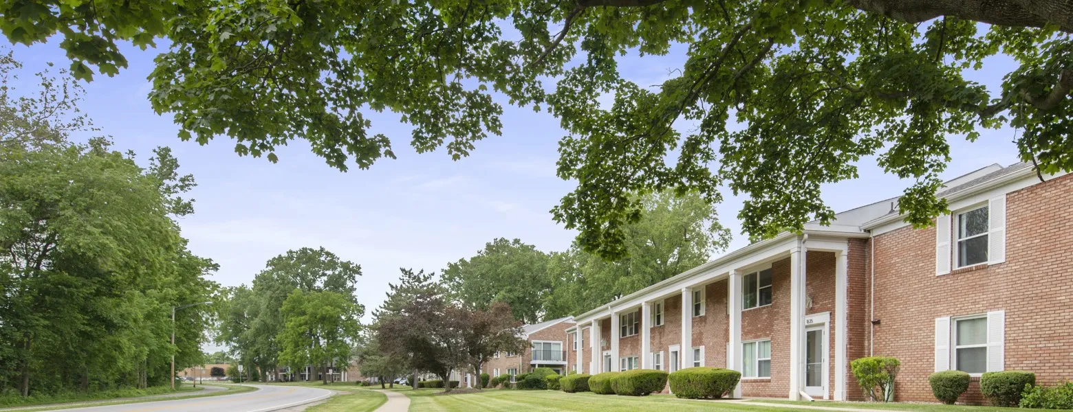 A row of buildings on the right curves alongside the road on the left. Trees are in abundance.
