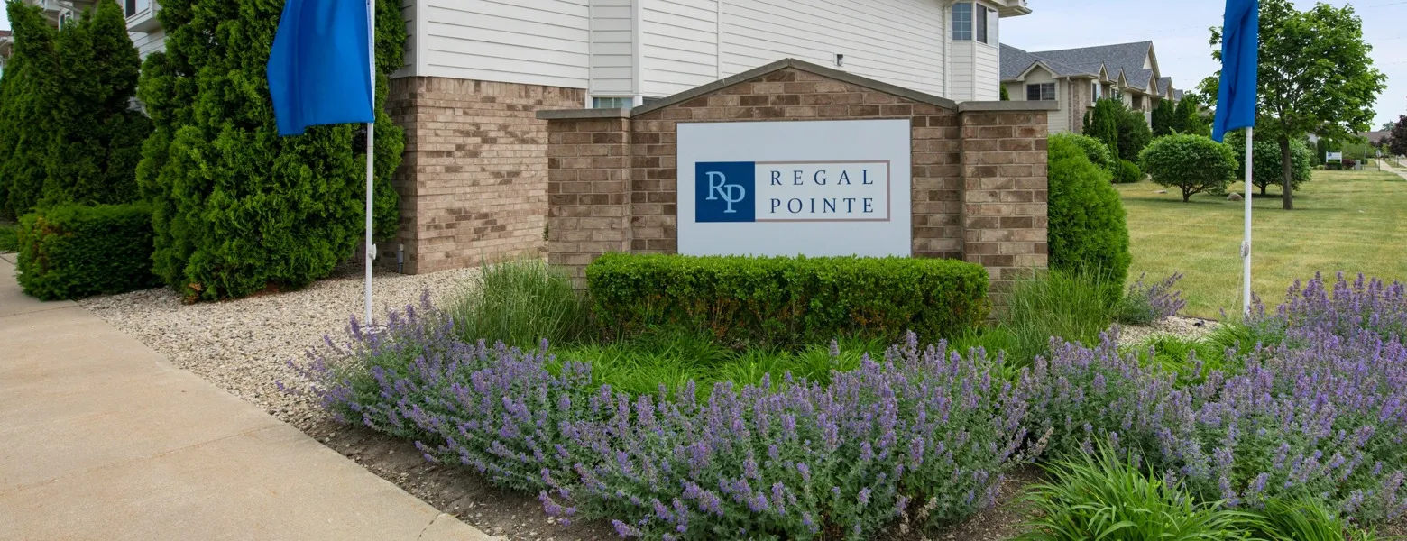 The Regal Pointe monument sign surrounded by purple flowers and lush green landscaping.
