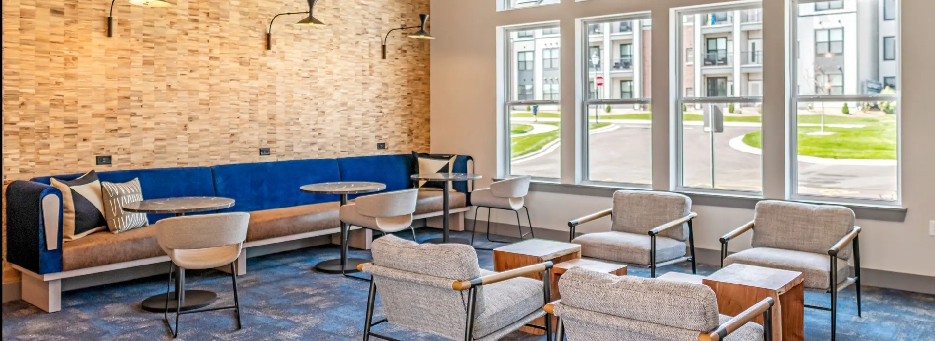 Clubhouse office seating area with a large bench seat along the back wall with small circle tables in front. Large windows along another wall allowing bright natural light into the room.vvvvvv