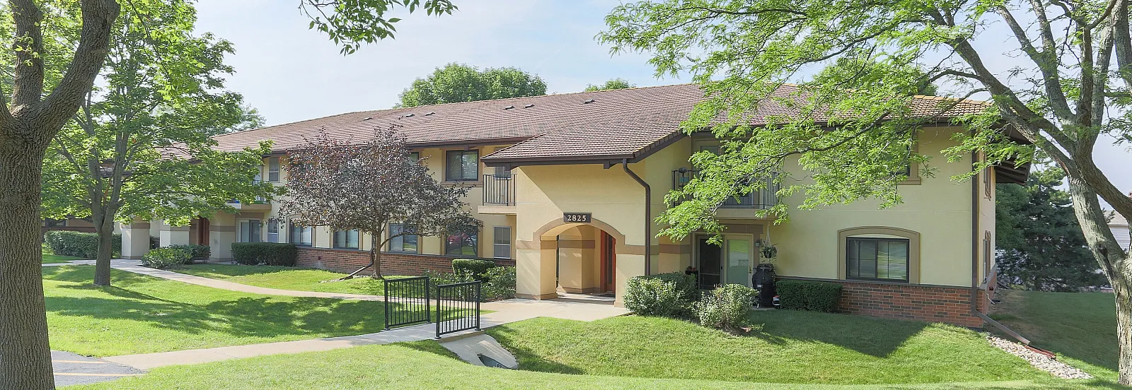 Charming two-story residential complex surrounded by lush greenery and mature trees.