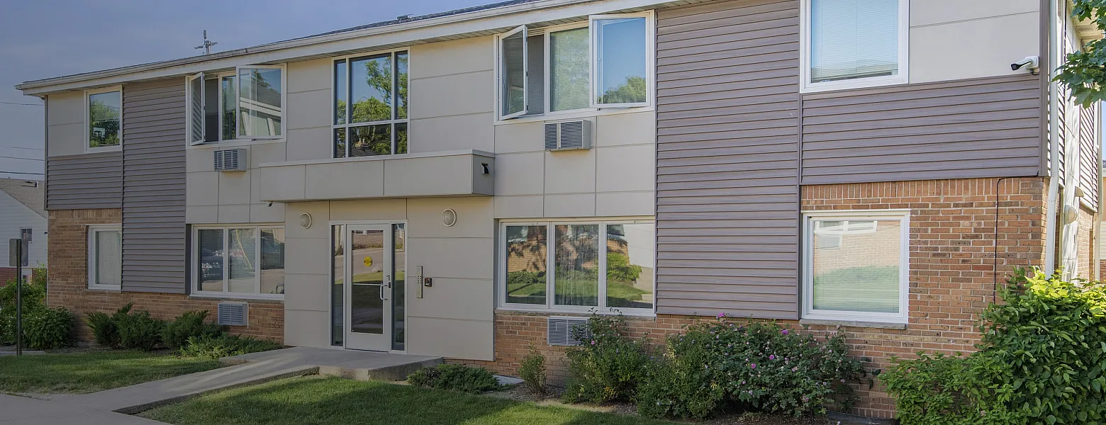Modern two-story apartment building with well-maintained lawn and large windows.