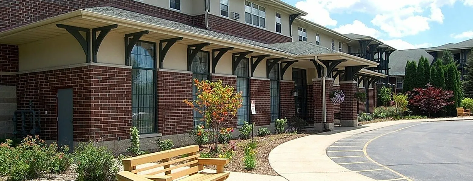 Elegant brick apartment building with landscaped garden and outdoor seating area.