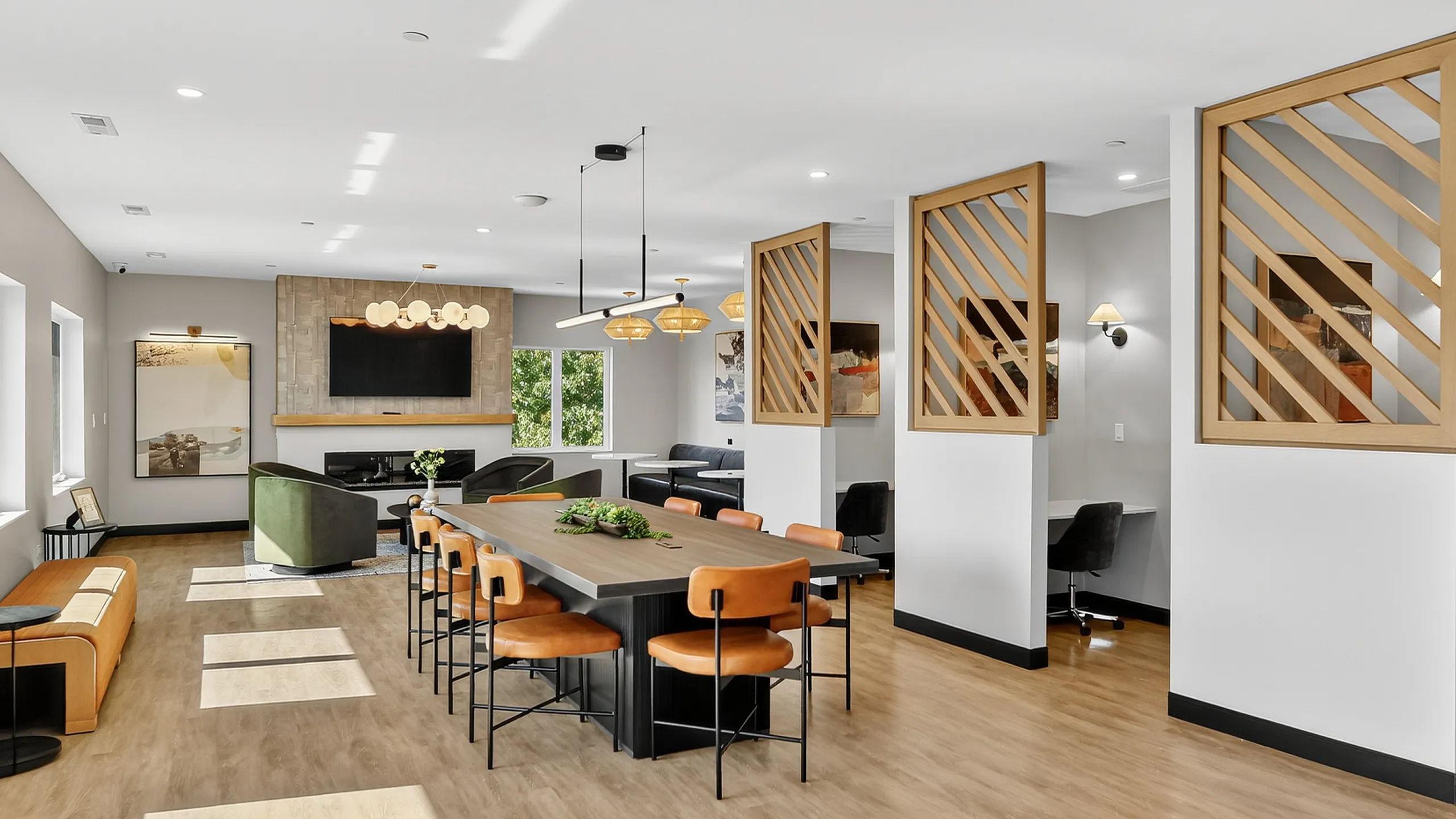 Modern communal space with a sleek wooden table, comfortable seating, stylish decor, and ample natural light, ideal for social gatherings.