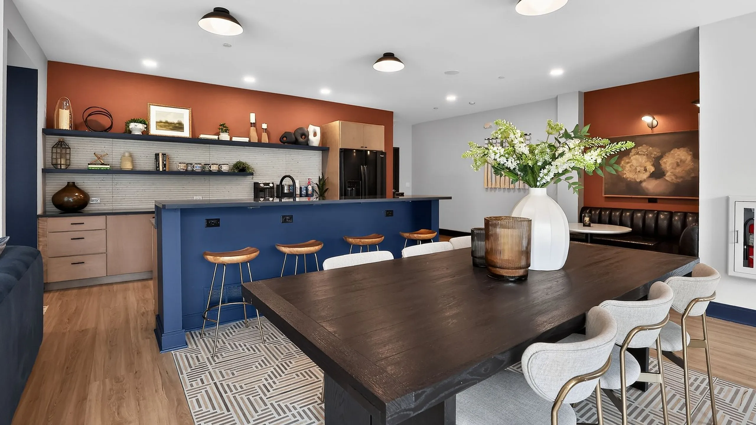 Modern kitchen and dining area with elegant decor, featuring a spacious island with bar stools, stylish wood flooring, and a chic dining table adorned with a floral centerpiece.