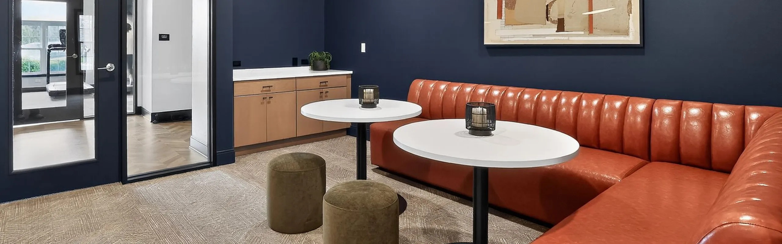 Modern lounge area with sleek navy walls, vibrant orange seating, and chic decor accents, perfect for relaxation and socializing.