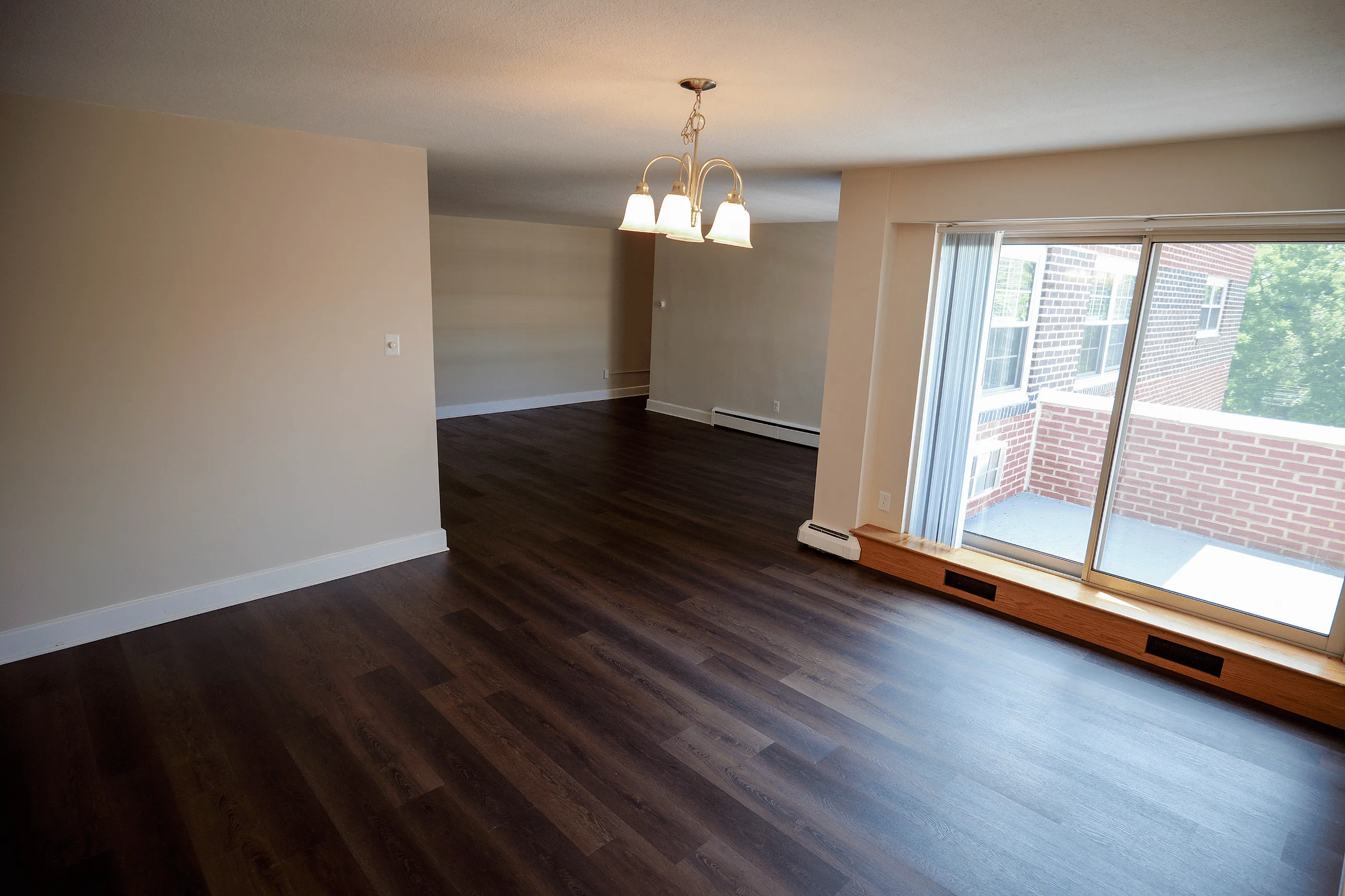 Open‑concept living room with vinyl flooring and balcony access in Bryn Mawr apartment
