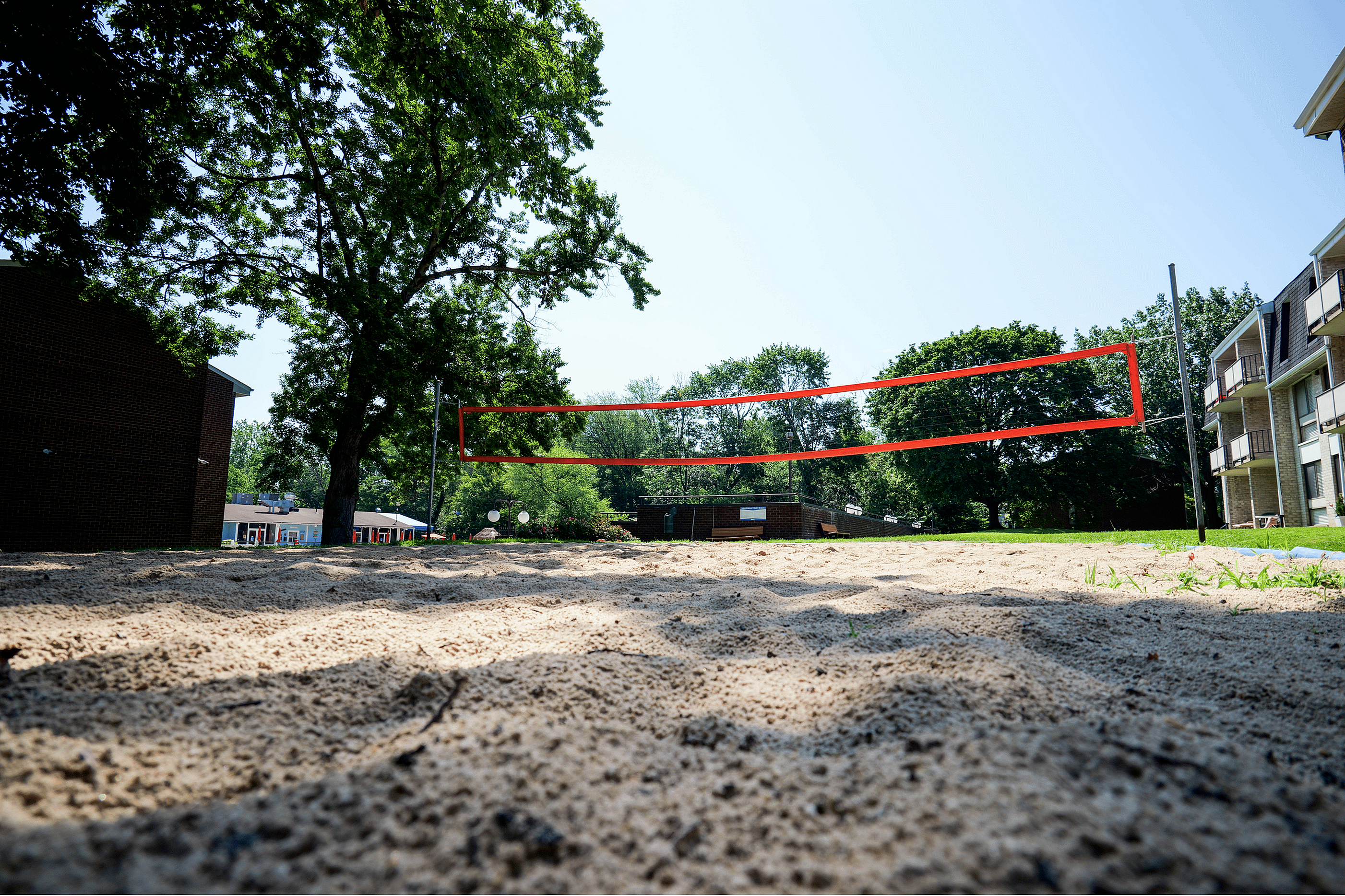 Inviting outdoor sand volleyball court surrounded by lush greenery and modern apartment buildings.