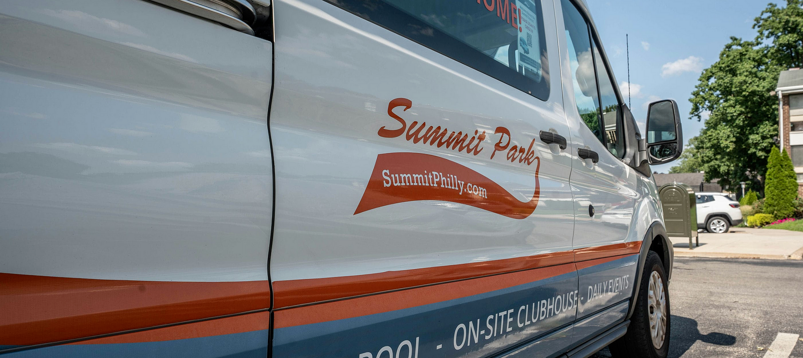 Bright, inviting van showcasing Summit Park branding, evoking community vibes and convenient on-site amenities against a sunny backdrop.