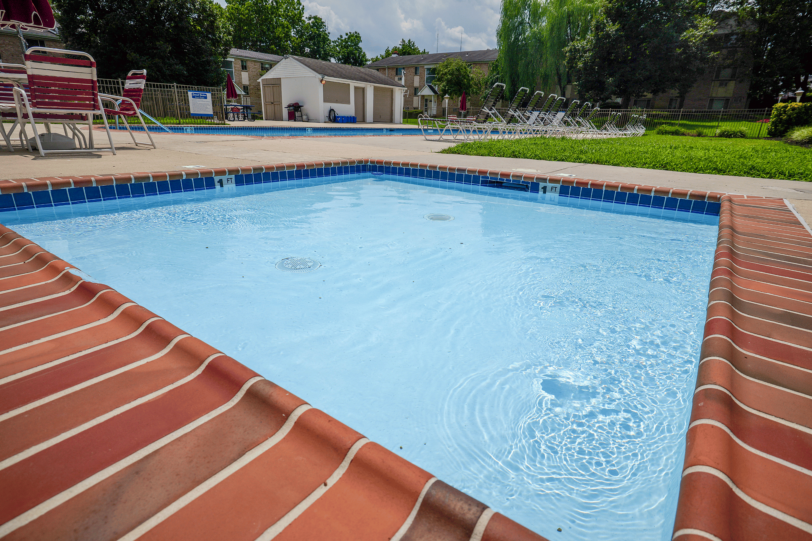 Inviting outdoor pool area with pristine water, surrounded by lush greenery and comfortable lounge chairs.