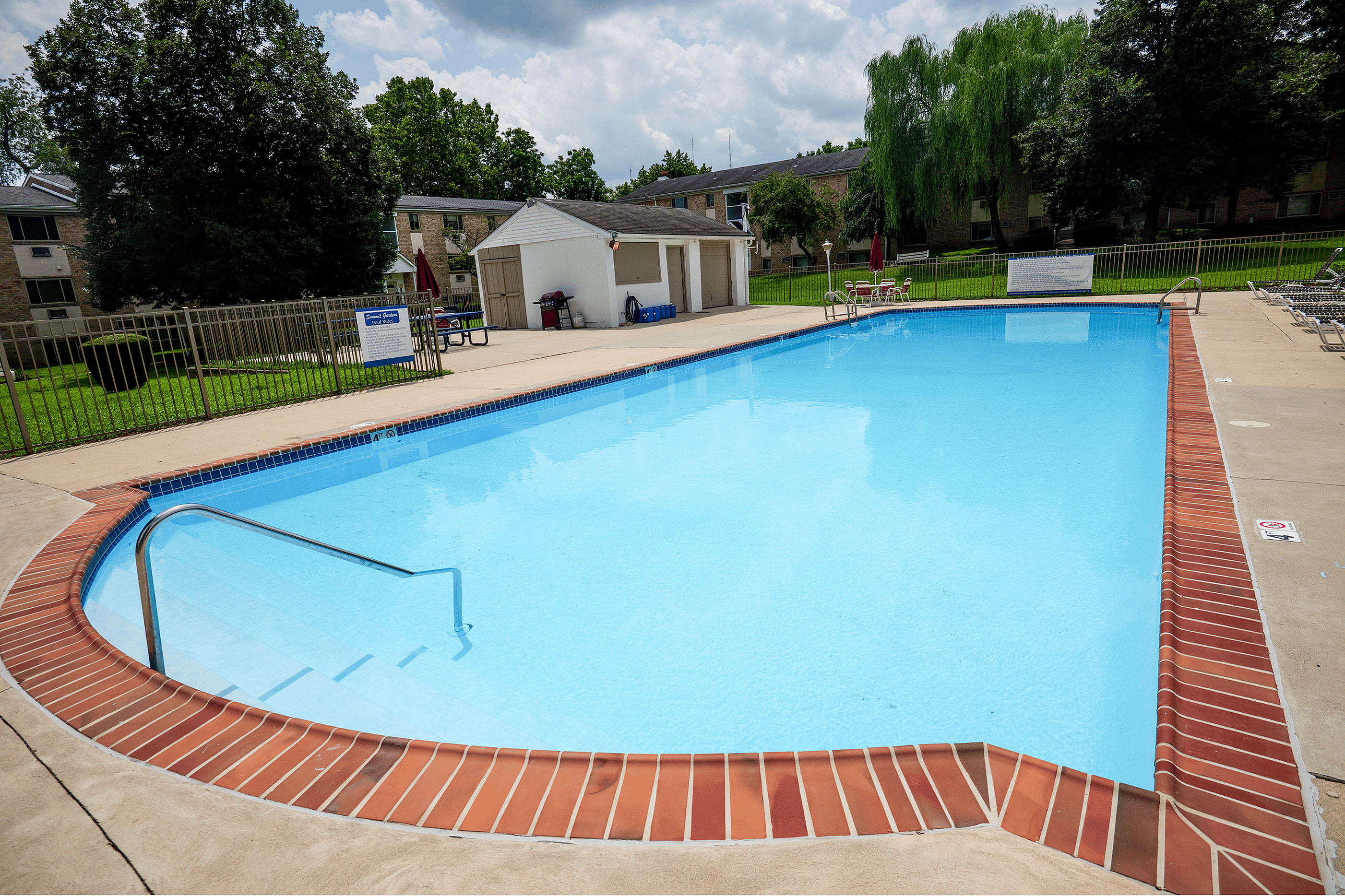 Inviting outdoor pool surrounded by lush greenery and a cozy seating area, perfect for summer relaxation.