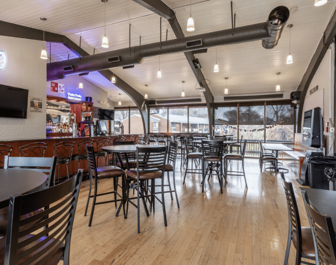 Chic community lounge with modern bar, ample seating, and large windows offering scenic outdoor views.