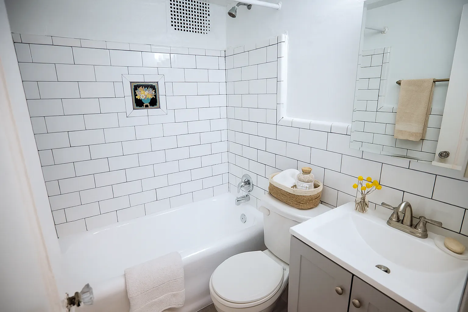 Charming bathroom with white subway tiles, a sleek vanity, and a relaxing bathtub, accentuated by a decorative wall tile and fresh, modern fixtures.