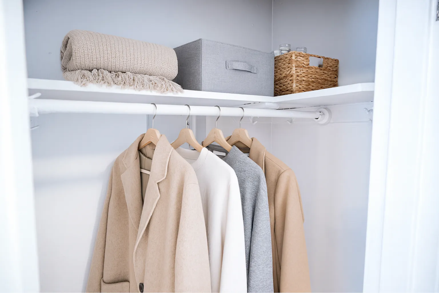 Elegant closet with neatly arranged neutral-toned coats and organized shelves, perfect for stylish living.