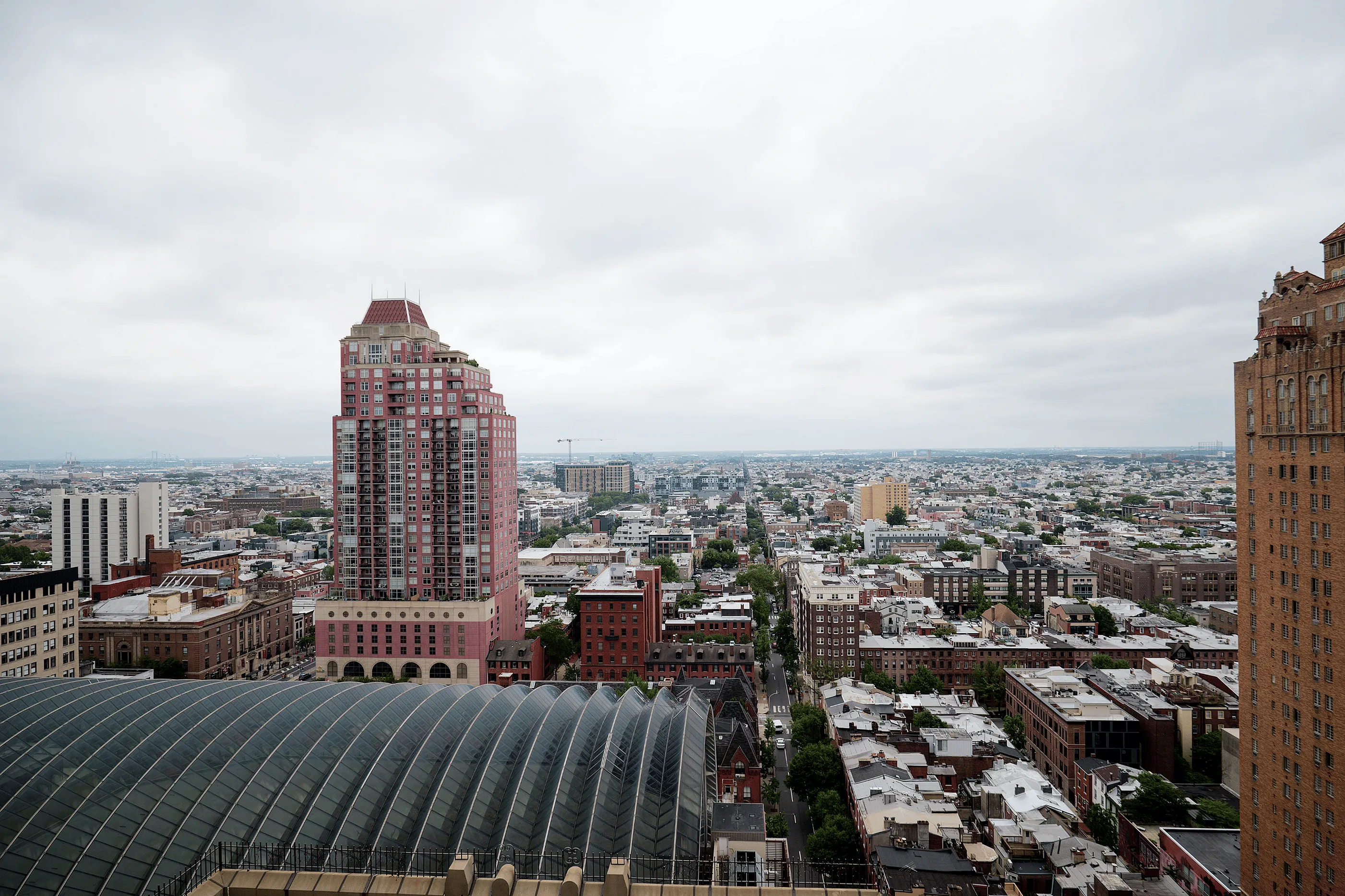 Breathtaking panoramic cityscape view featuring a red high-rise building and elegant architecture under a cloudy sky.