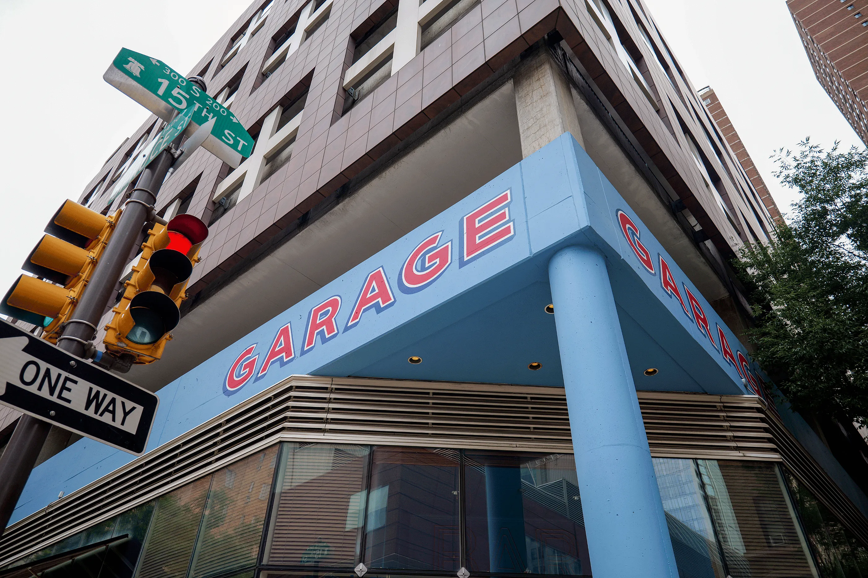 Modern urban building corner featuring a bold blue garage entrance with street signs and a traffic light, symbolizing city convenience.